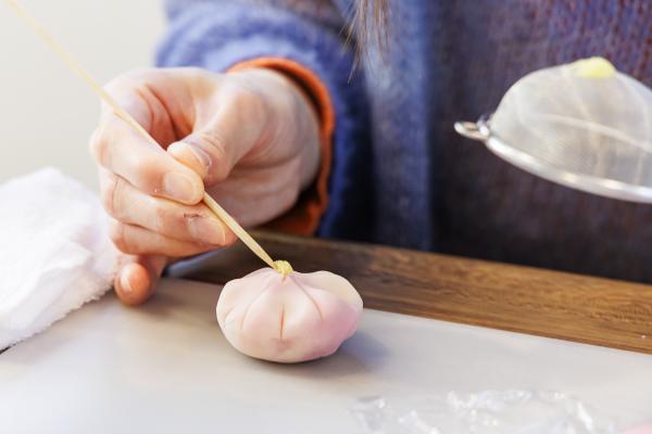 黄色の餡を爪楊枝で花にのせている手元の写真